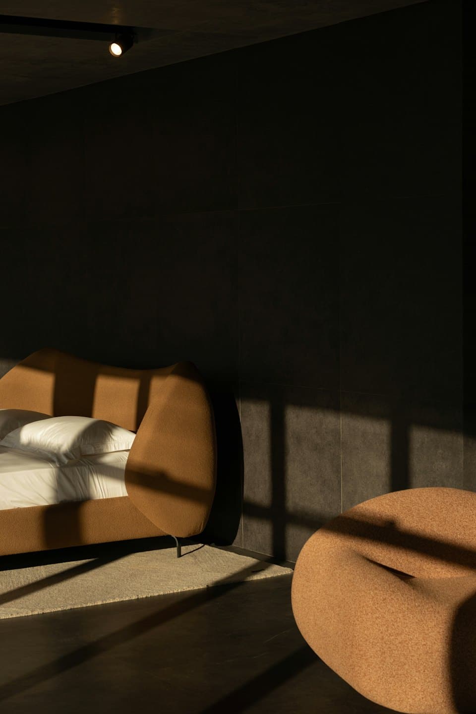 Terracotta upholstered bed and seating in a sunlit modern bedroom.