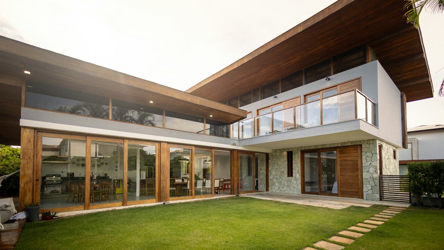 Modern house with glass doors and wood accents overlooking a lawn.