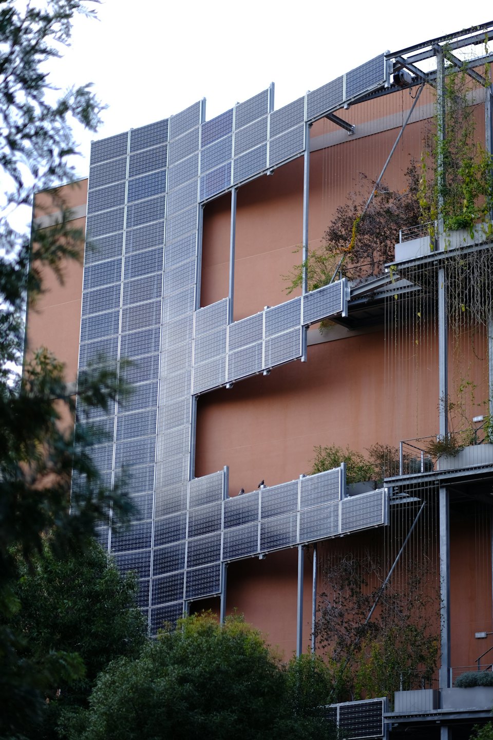 Building facade with solar panels and vertical gardens.