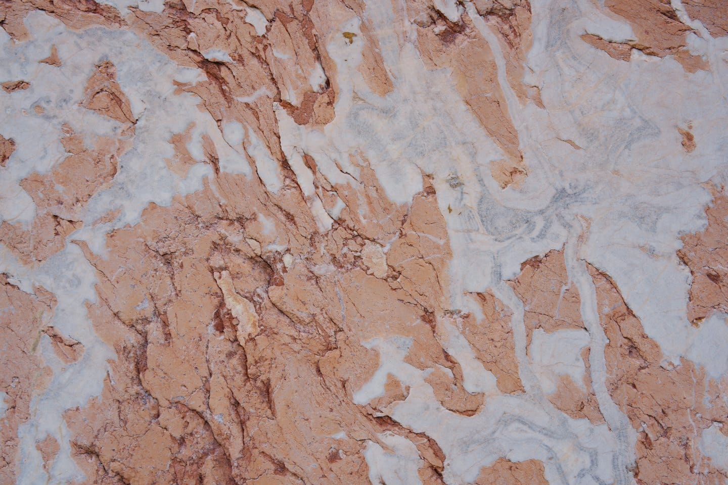 Natural stone surface with reddish-brown and white patterns.